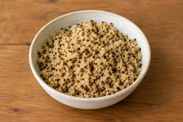 Bowl of cooked quinoa on a wooden table