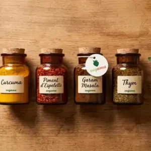 Four amber glass spice jars with cork lids: curcuma, piment d'Espelette, garam masala and thyme